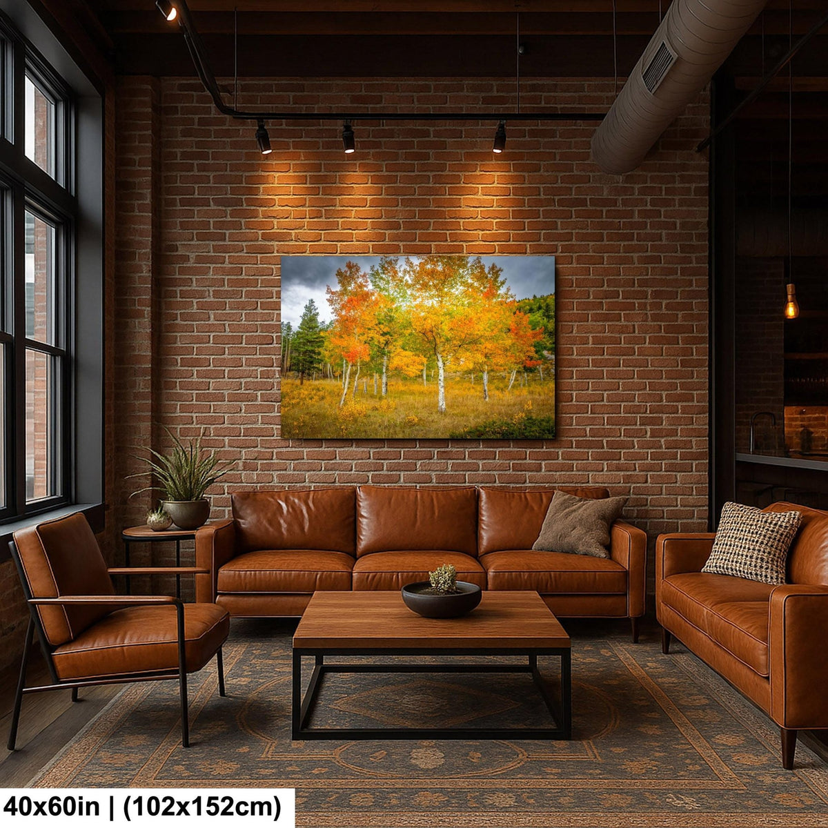 a cozy living room with a brick wall, a large painting of a forest scene, and a wooden coffee table surrounded by brown leather furniture.