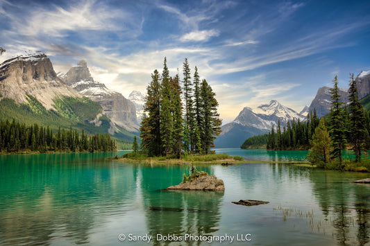Sprit Island at Maligne Lake in Jasper National Park, Canada. Beautiful blue skies and wispy clouds over incredible green water. Landscape photography available in canvas or paper prints for home or office decor.