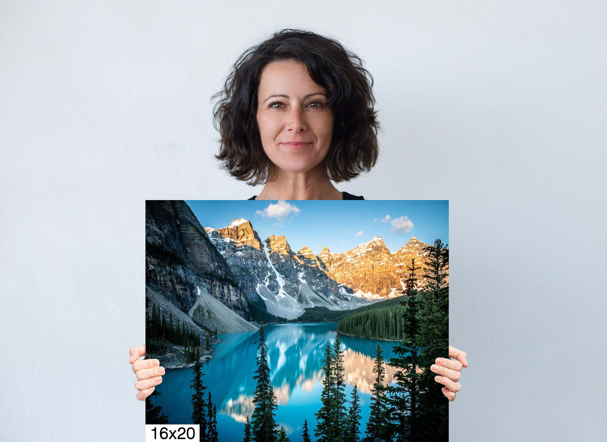 Woman holding 16x20 canvas print of Moraine Lake Sunrise in Banff National Park. A dramatic landscape of vivid color, good for home or office decor.
