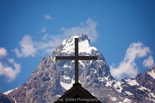 Cross on top of the Chapel of the Transfiguration against the mountain peak of the Grand Tetons in Grand Teton National Park, Wyoming. Inspirational mountain scenery offered in canvases and fine art print.