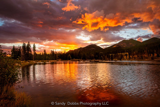 Vivid sunrise at Sprague Lake in Rocky Mountain National Park, Colorado. Rich hues of red and orange creating a dramatic landscape photo. Available in fine art prints and canvases.
